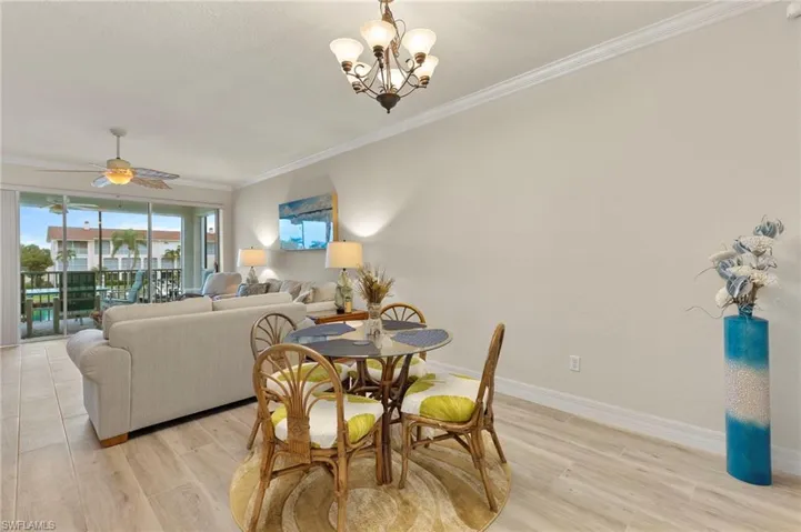 Dining space with ceiling fan with notable chandelier, ornamental molding, and light hardwood / wood-style flooring
