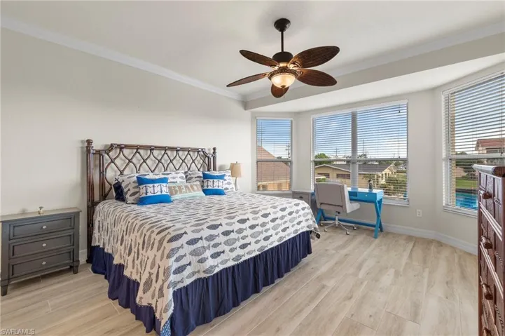 Bedroom with ceiling fan, light hardwood / wood-style floors, and crown molding
