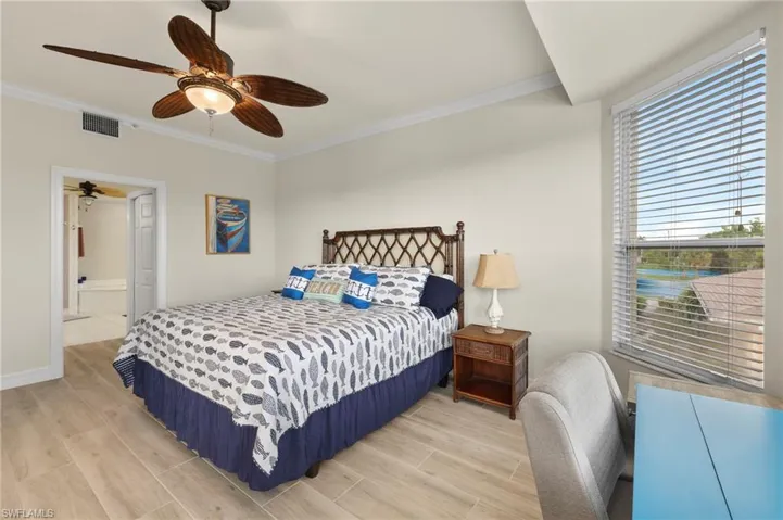 Bedroom featuring ceiling fan, hardwood / wood-style floors, ensuite bath, and ornamental molding