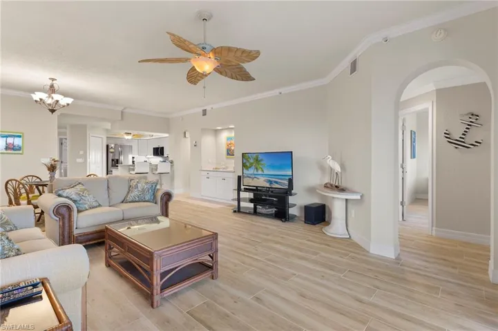 Living room featuring ceiling fan with notable chandelier and crown molding