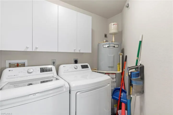 Laundry area with cabinets, electric dryer hookup, water heater, hookup for a washing machine, and washer and dryer
