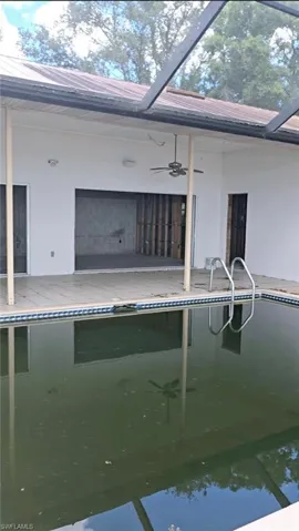 Back of property featuring ceiling fan and glass enclosure