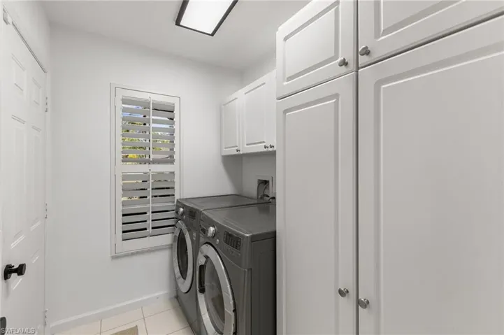 Laundry room featuring cabinet space, light tile patterned floors, and washer and clothes dryer