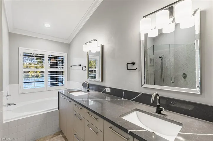 Full bathroom featuring a stall shower, double vanity, a garden tub, and crown molding