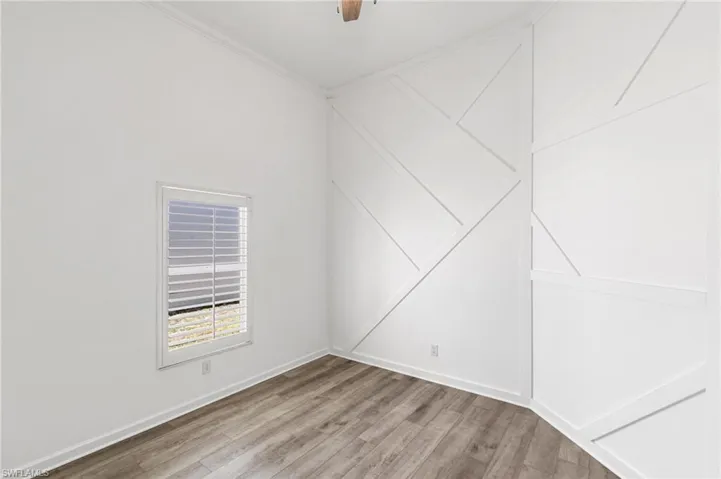 Empty room featuring light wood-type flooring, ornamental molding, and a ceiling fan