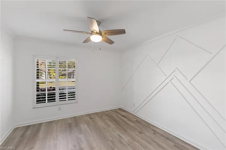 Spare room with ornamental molding, light wood-style flooring, and ceiling fan
