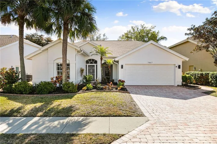 Ranch-style home featuring decorative driveway, stucco siding, a front lawn, and an attached garage
