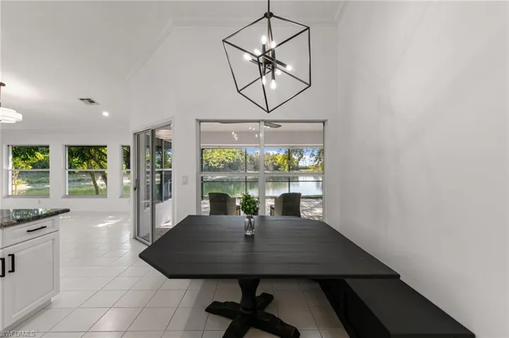 Dining room featuring suspended lighting, crown molding, light tile patterned floors, a water view, and a high ceiling