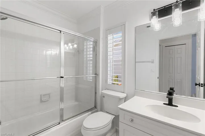 Bathroom with enclosed tub / shower combo, vanity, and crown molding