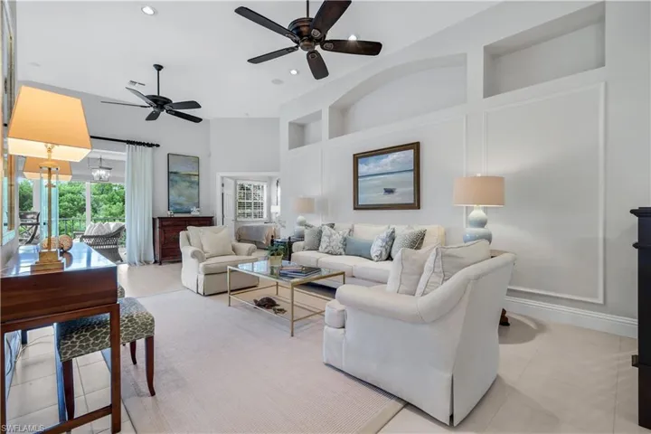 Living room with built in features, light tile patterned floors, recessed lighting, a ceiling fan, and a high ceiling
