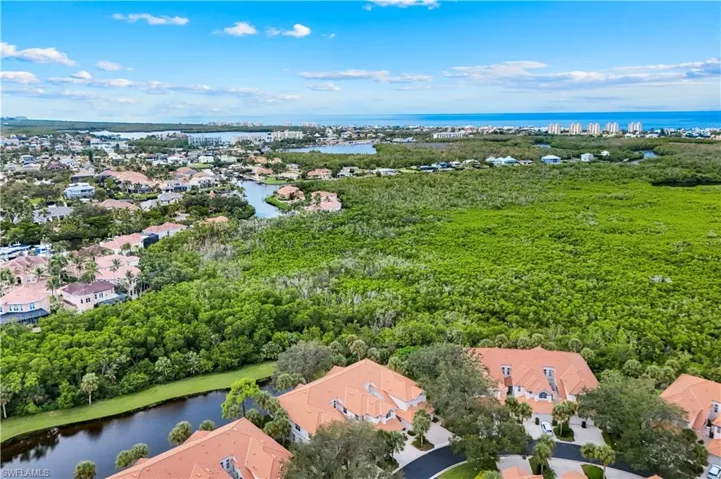 Aerial view of residential area with a nearby body of water and a tree filled landscape