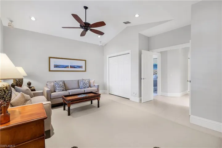 Living area with vaulted ceiling, recessed lighting, ceiling fan, light tile patterned flooring, and light colored carpet