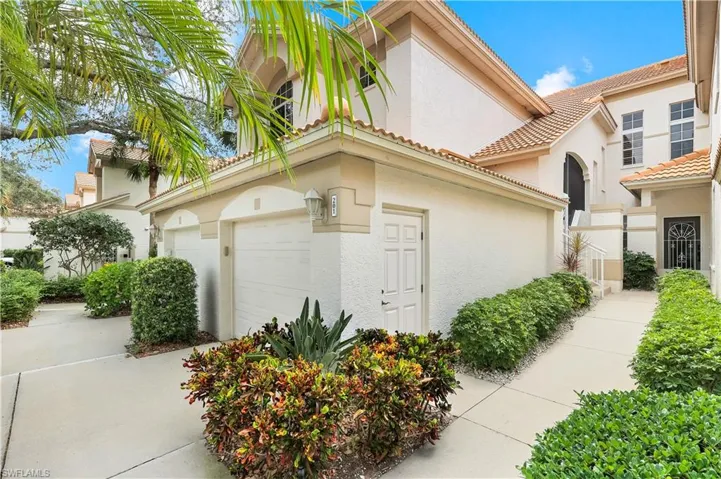 View of front of property featuring stucco siding, a tile roof, an attached garage, and driveway