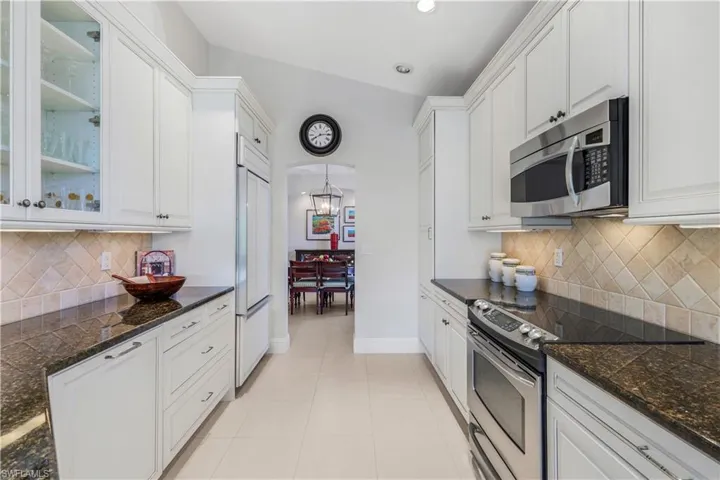 Kitchen featuring tasteful backsplash, appliances with stainless steel finishes, white cabinetry, light tile patterned flooring, and recessed lighting