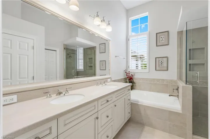 Bathroom with a shower stall, double vanity, a garden tub, light tile patterned floors, and a closet