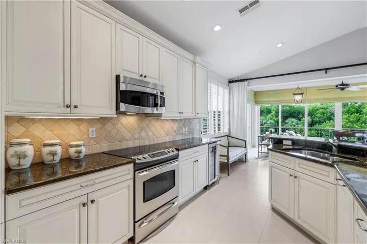Kitchen with vaulted ceiling, appliances with stainless steel finishes, recessed lighting, light tile patterned floors, and decorative backsplash