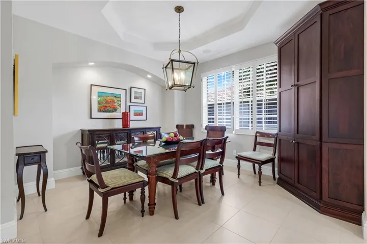 Dining area featuring a raised ceiling, a chandelier, and light tile patterned floors