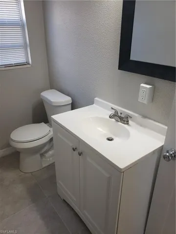 Bathroom featuring a textured wall, vanity, and tile patterned flooring