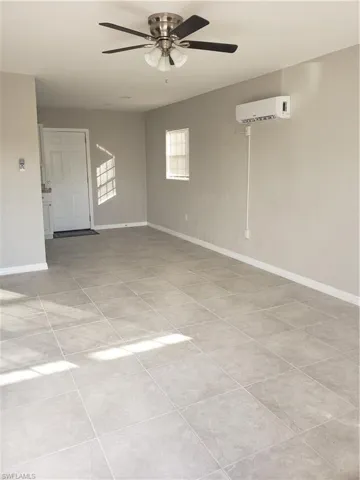 Unfurnished room with light tile patterned floors, a ceiling fan, and a wall mounted air conditioner