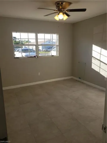 Empty room with baseboards and a ceiling fan
