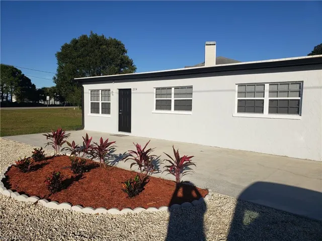 View of side of home featuring a chimney, stucco siding, and a yard