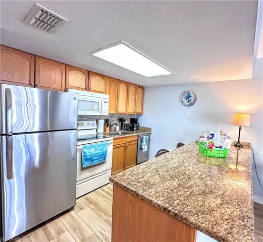 Kitchen featuring appliances with stainless steel finishes, light wood-style floors, a peninsula, backsplash.