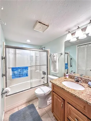 Bathroom with vanity, shower / bath combination with glass door and tile