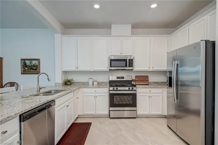 Kitchen featuring stainless steel appliances, white cabinetry, light stone countertops, and recessed lighting