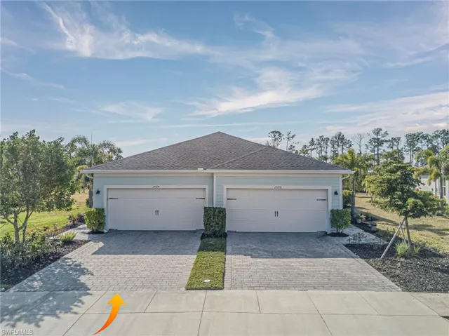View of front of house featuring driveway, roof with shingles, and a garage