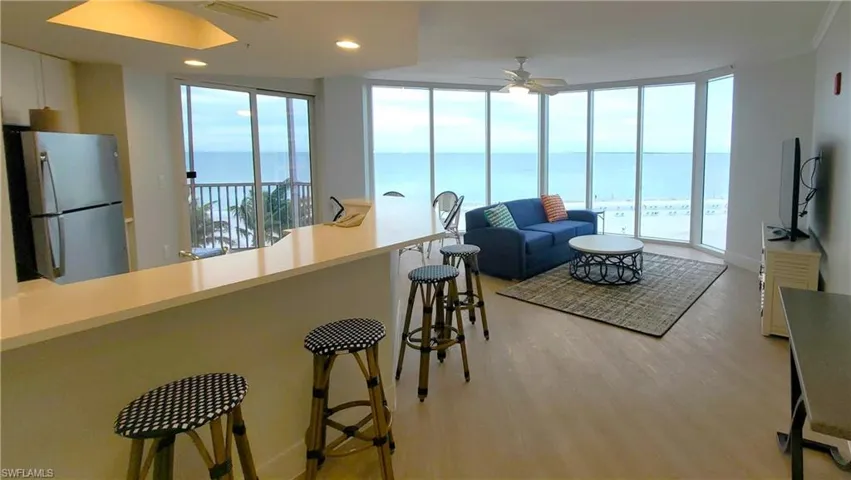 Living room featuring a water view, a wall of windows, recessed lighting, a ceiling fan, and light wood-style floors