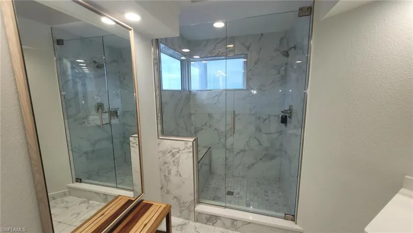 Full bathroom featuring marble finish floor, a textured wall, and a marble finish shower