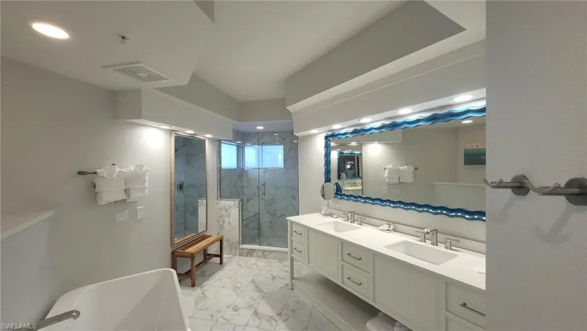 Bathroom with marble finish floor, visible vents, a sink, and a marble finish shower