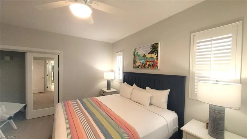 Bedroom with lofted ceiling, multiple windows, a ceiling fan, and light carpet