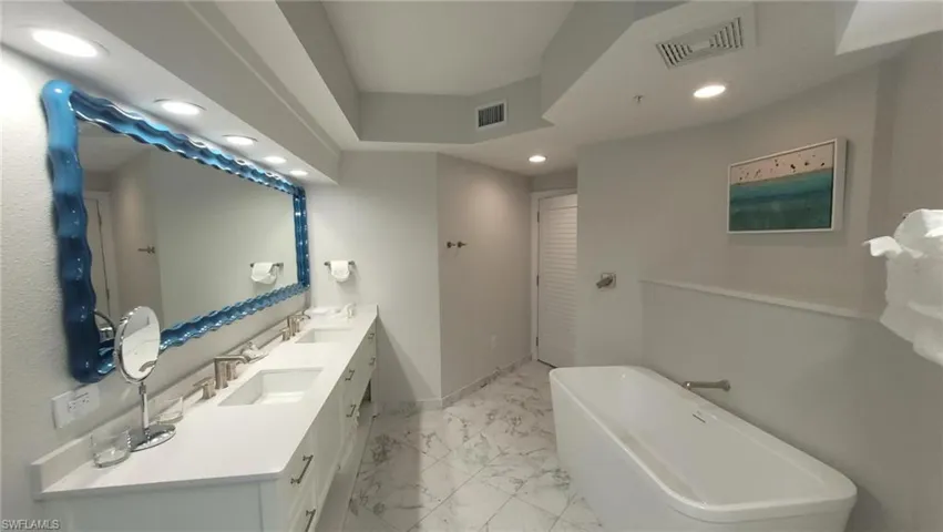 Full bath featuring visible vents, a sink, marble finish floor, and a freestanding bath