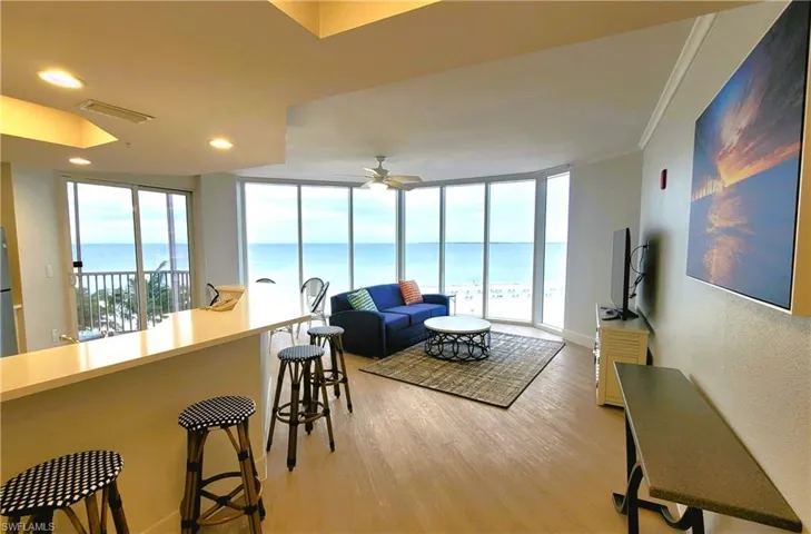 Living area with light wood-style flooring, recessed lighting, a wall of windows, a water view, and a ceiling fan