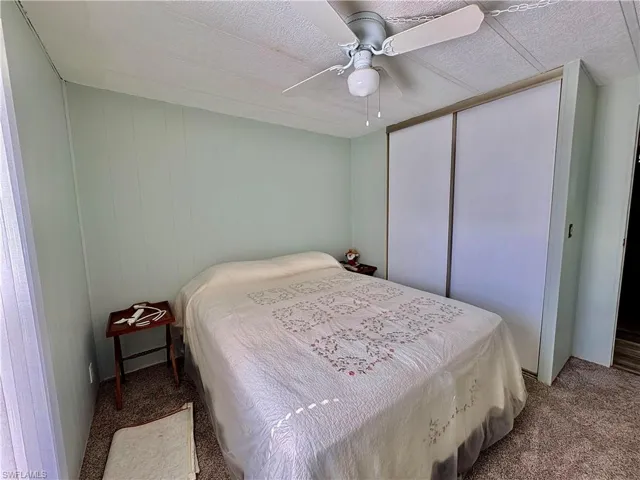 Bedroom with carpet, ceiling fan, a textured ceiling, and a closet