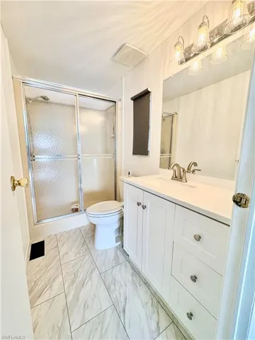 Bathroom featuring vanity, a shower stall, and light marble finish flooring