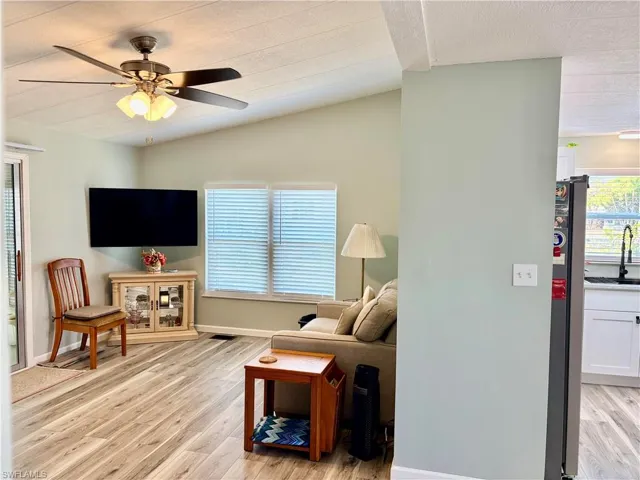 Living room with light wood-type flooring, ceiling fan, plenty of natural light, and lofted ceiling