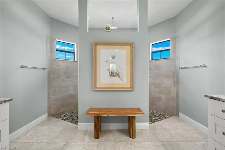 Bathroom featuring vanity, tiled shower, and tile patterned flooring
