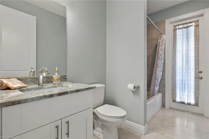 Full bathroom featuring shower / tub combo with curtain, vanity, tile patterned floors, and toilet