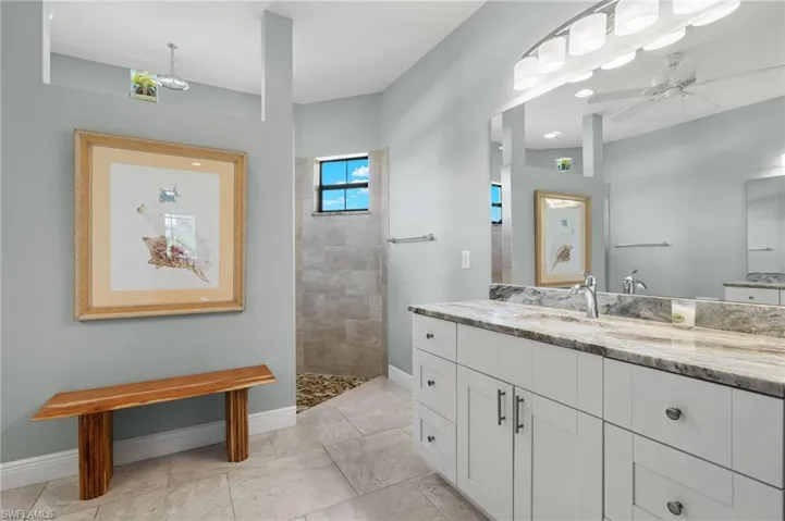 Bathroom featuring tiled shower, vanity, ceiling fan, and tile patterned floors
