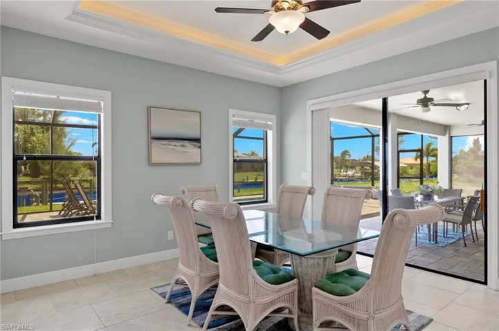 Tiled dining room featuring plenty of natural light, a raised ceiling, and ceiling fan