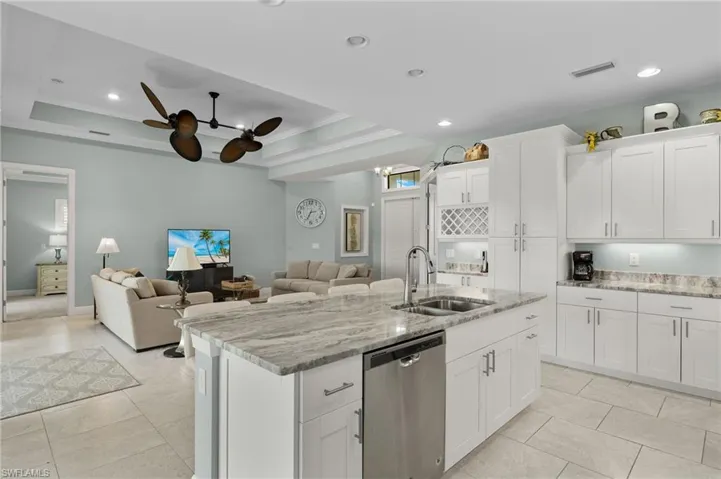 Kitchen featuring sink, stainless steel dishwasher, ceiling fan, and a tray ceiling