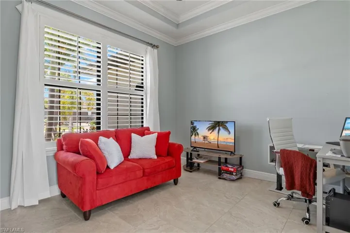 Tiled office with a tray ceiling, a healthy amount of sunlight, and ornamental molding