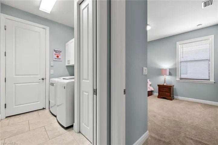 Laundry area featuring cabinets, light tile patterned flooring, and independent washer and dryer