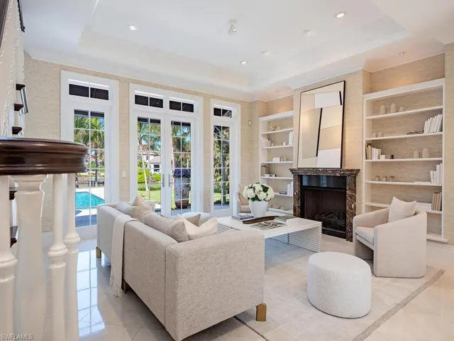 Tiled living room featuring a raised ceiling, built in shelves, a premium fireplace, and crown molding
