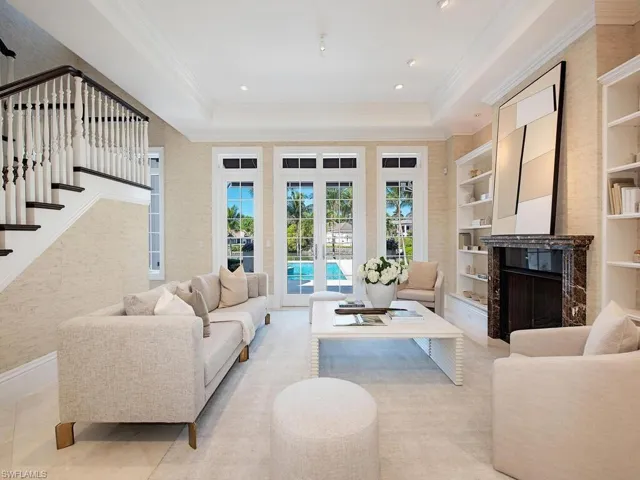 Living room with light tile patterned floors, a tray ceiling, built in features, and ornamental molding