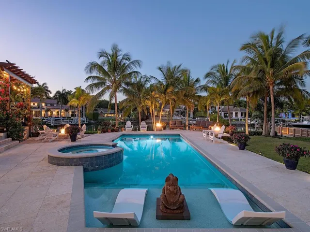 Pool at dusk featuring an in ground hot tub and a patio