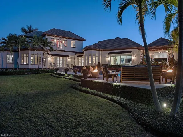 Back house at dusk with a lawn, an outdoor living space, and a patio area