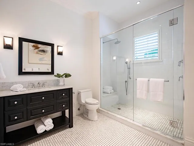 Bathroom with ornamental molding, vanity, a shower with door, tile patterned flooring, and toilet